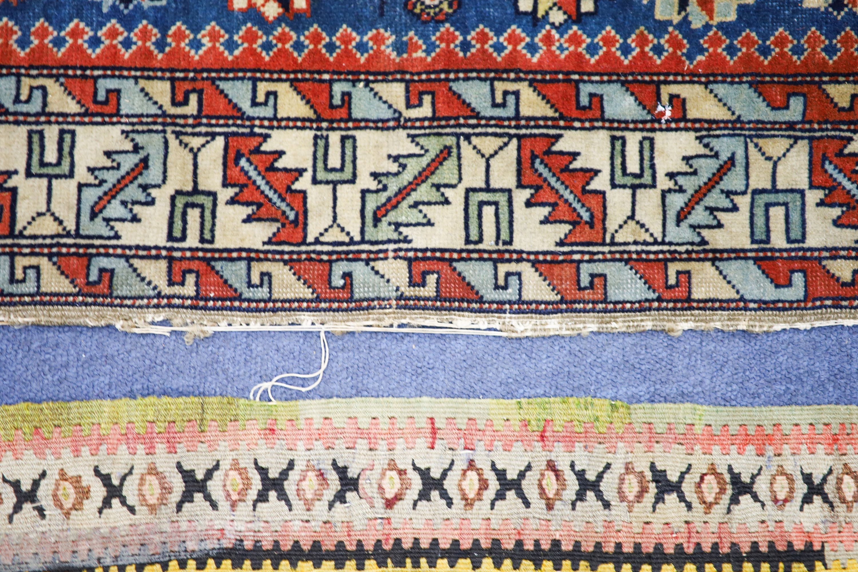 A Caucasian blue ground rug with triple medallions and geometric border, 144 x 89 cm.